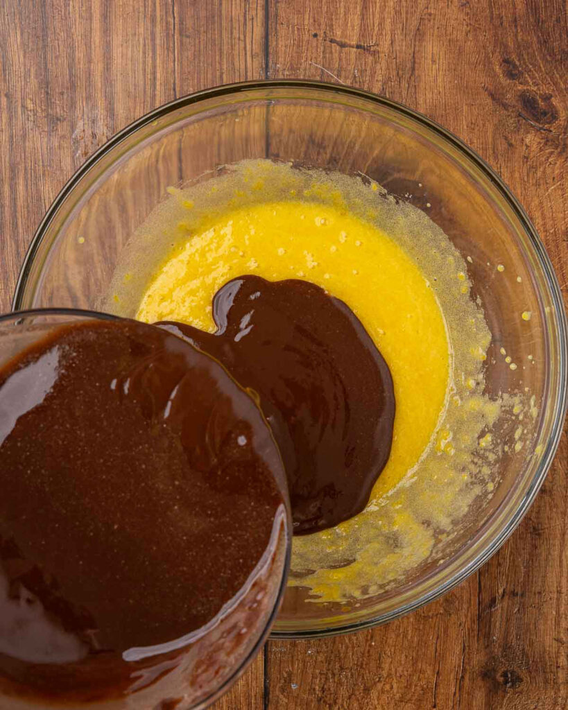 Pouring melted butter and chocolate in a bowl with egg yolks.