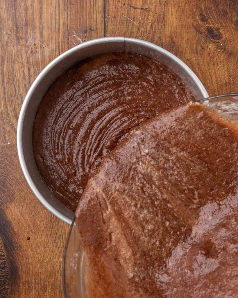 Pouring the chocolate beet cake batter from the bowl into a springform pan.