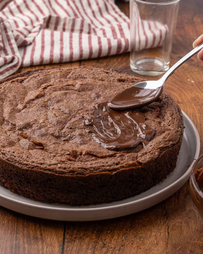 A spoon adding chocolate glaze to the chilled chocolate beet cake.