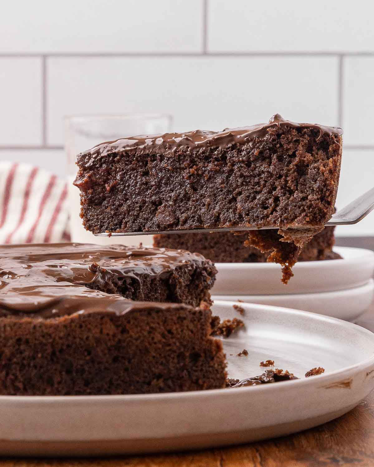 A spatula removing a slice of chocolate beet cake from a white serving tray.