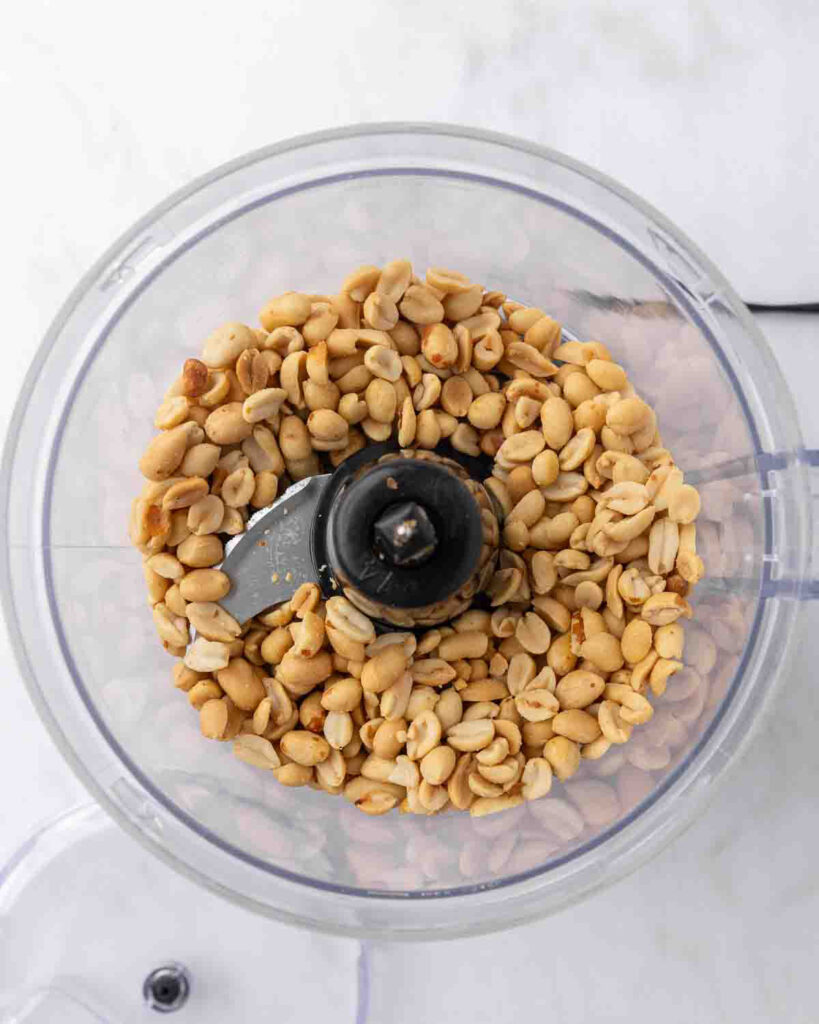 Peanuts in a food processor ready to be ground into peanut butter.