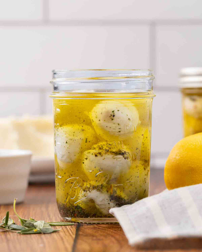 A jar of marinated mozzarella balls sitting on a counter.