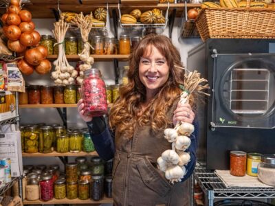 A woman in a pantry holding up food.