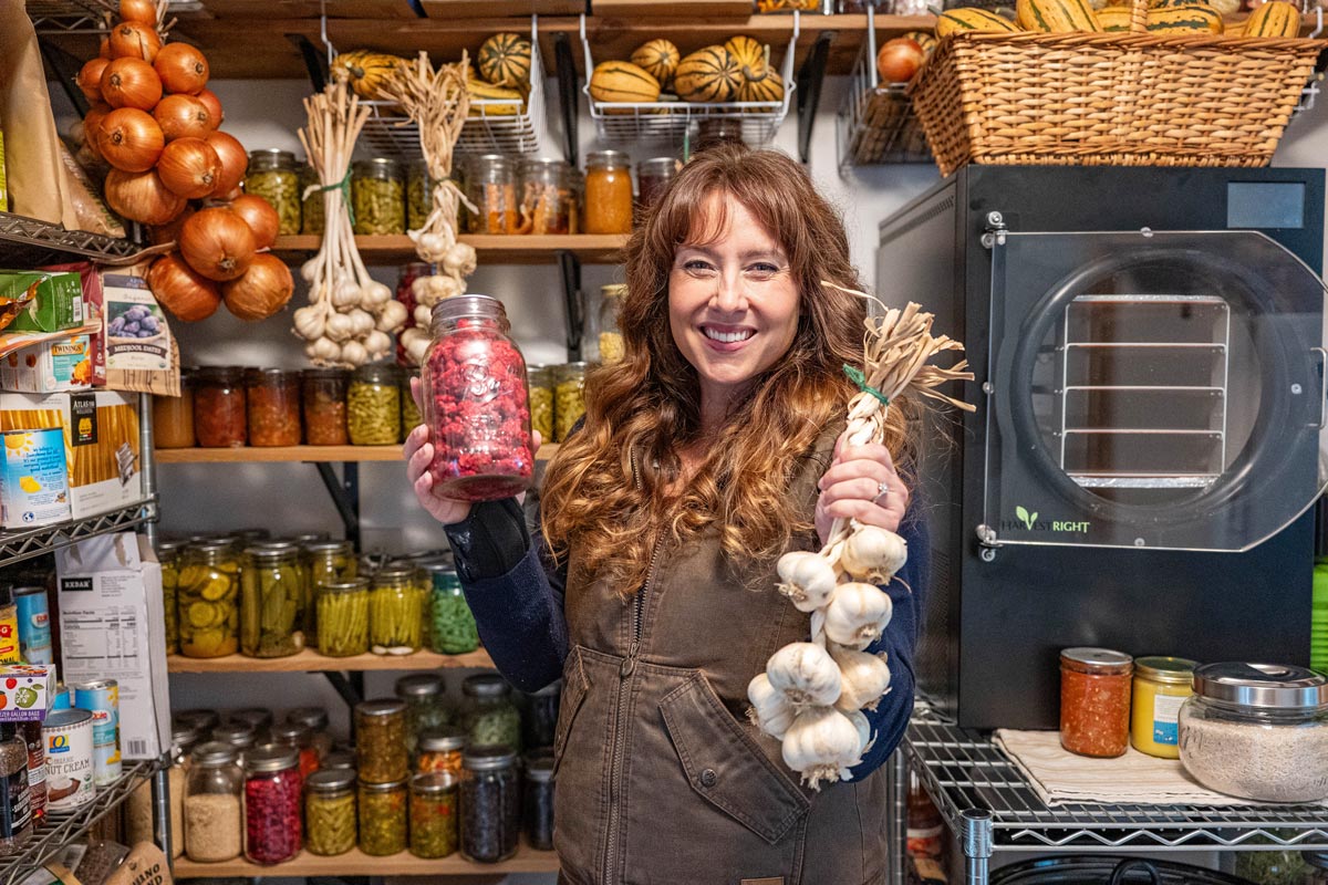 A woman in a pantry holding up food.