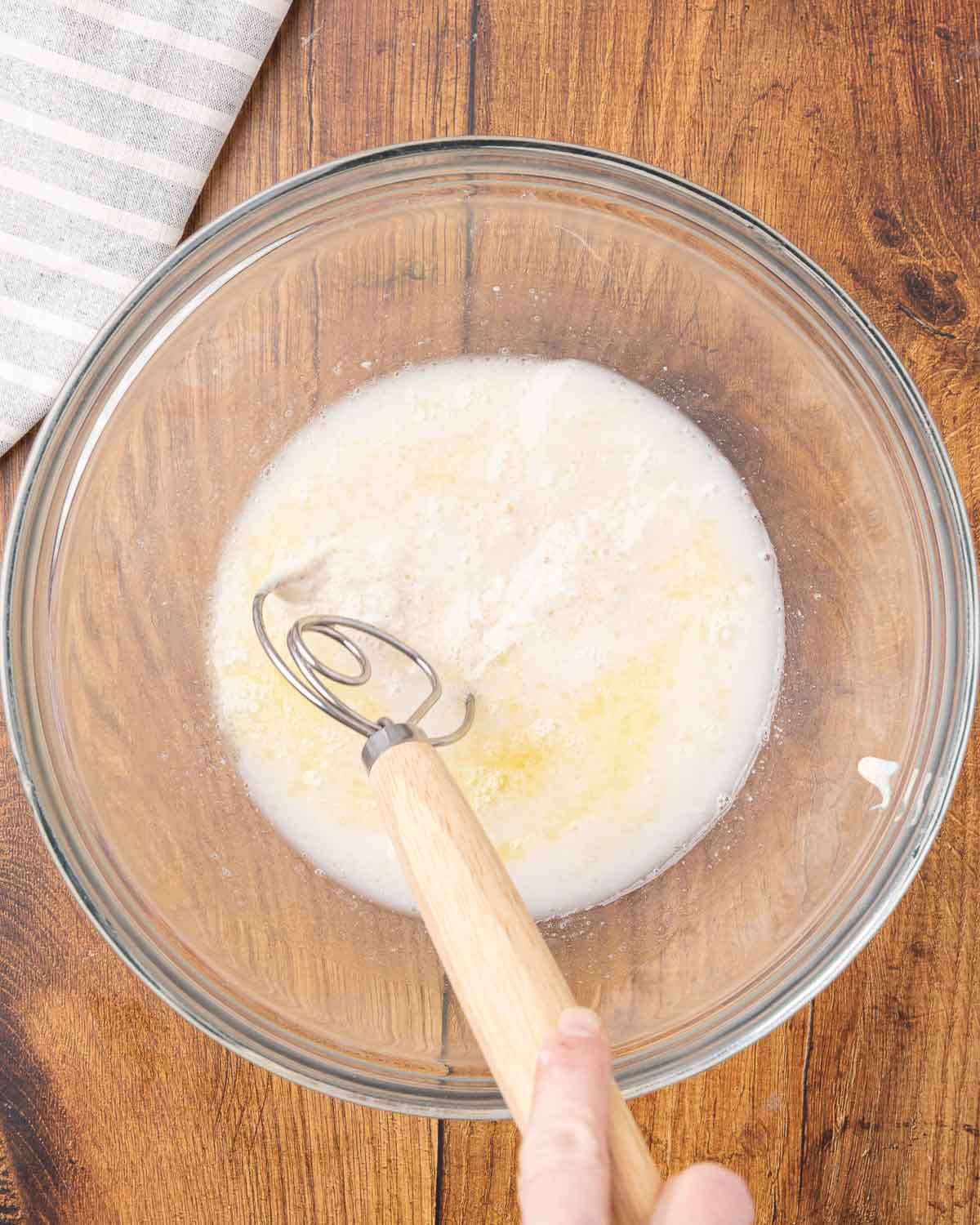 Water and sourdough starter being mixed in a bowl.