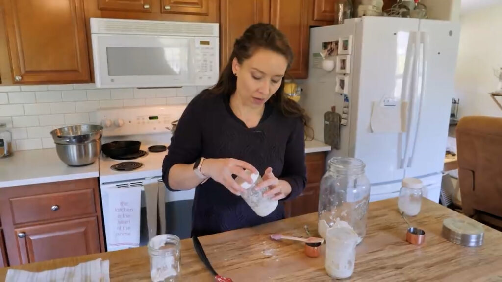 A woman placing a lid on the jar of sourdough starter.