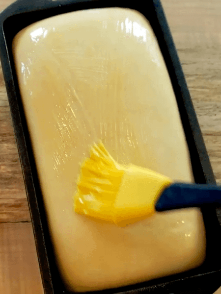 A loaf of bread being buttered.