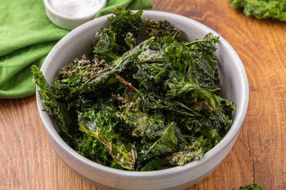 Baked kale chips served in a white bowl.