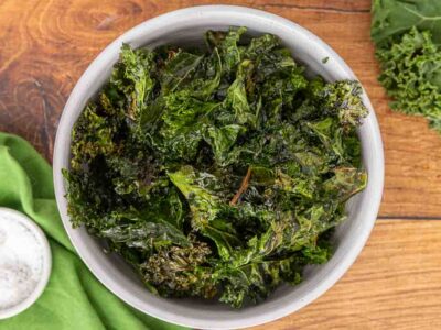 Baked kale chips served in a white bowl.