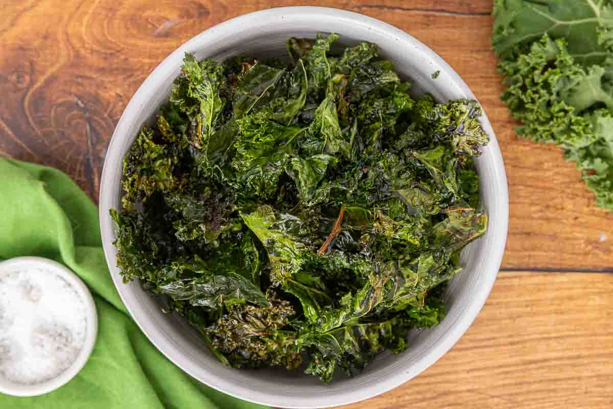 Baked kale chips served in a white bowl.