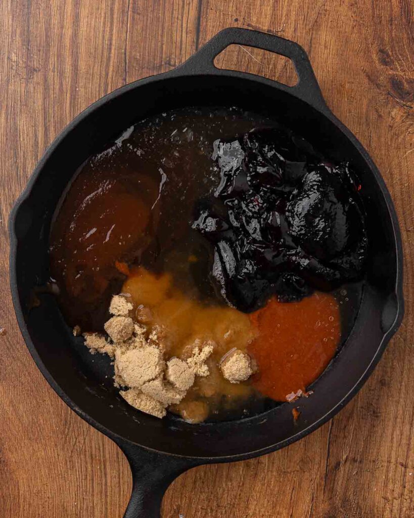 Cocktail meatball sauce ingredients in a cast iron pan.