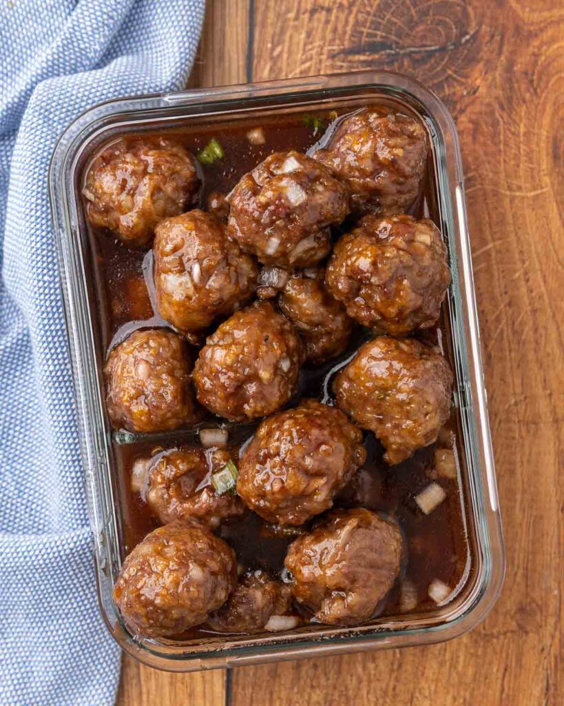 Leftover cocktail meatballs and sauce in a container ready for storage.