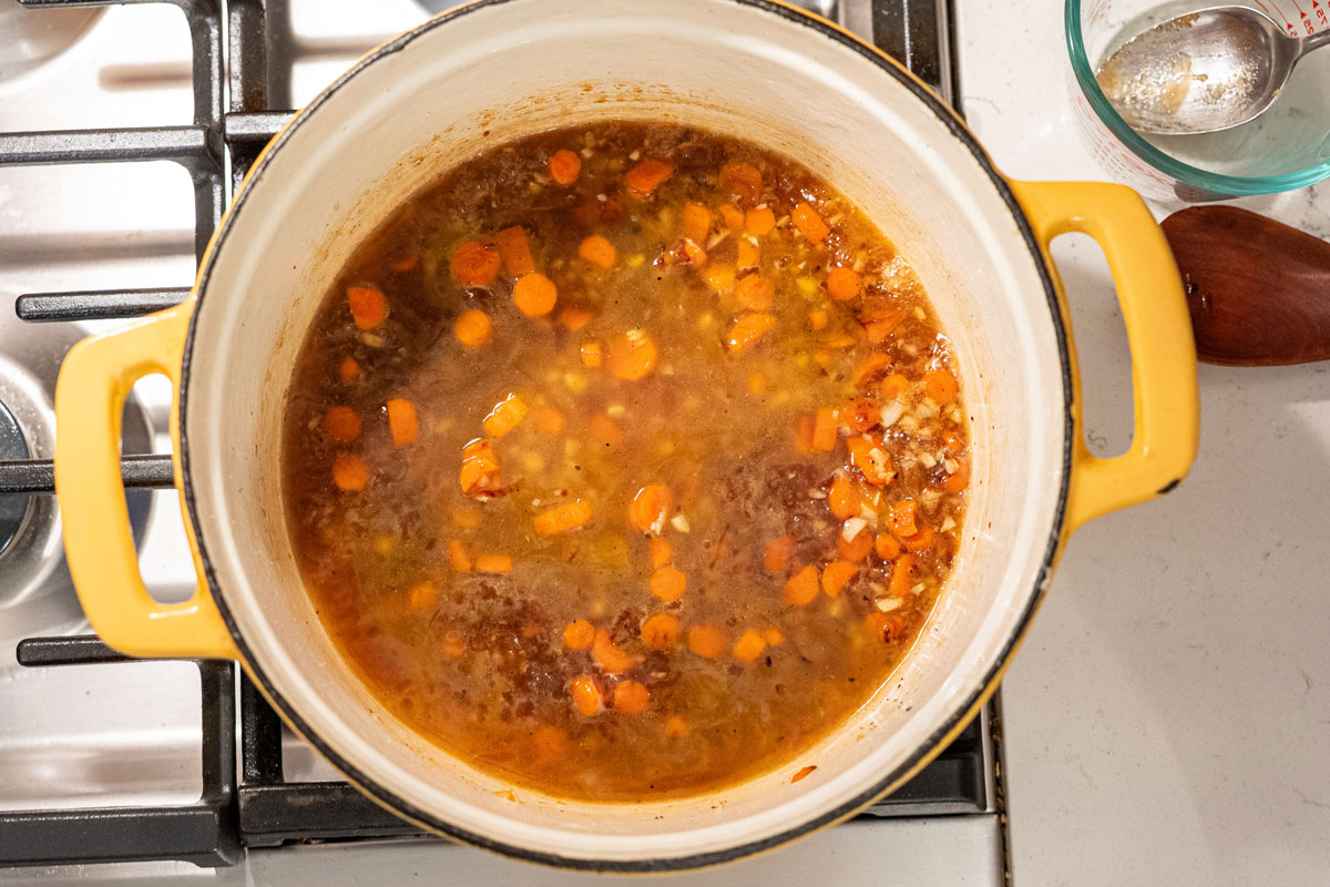 Veggies and broth simmering in a Dutch oven.