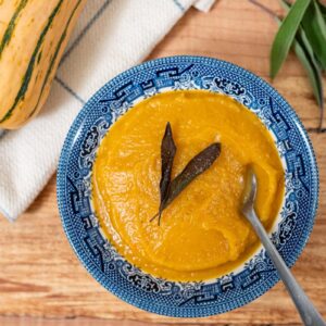 A bowl of Delicata squash soup with a fried sage leaf on top.