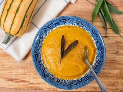 A bowl of Delicata squash soup with a fried sage leaf on top.