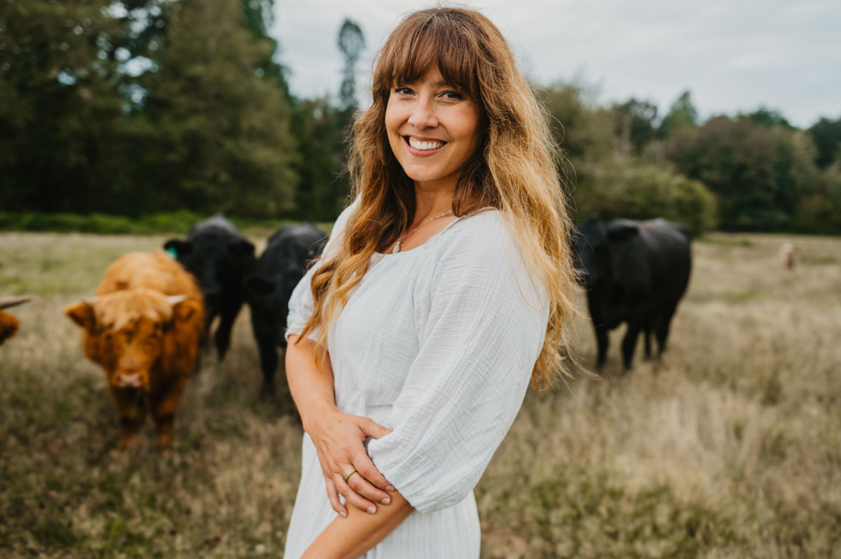 A woman in a field with cows.