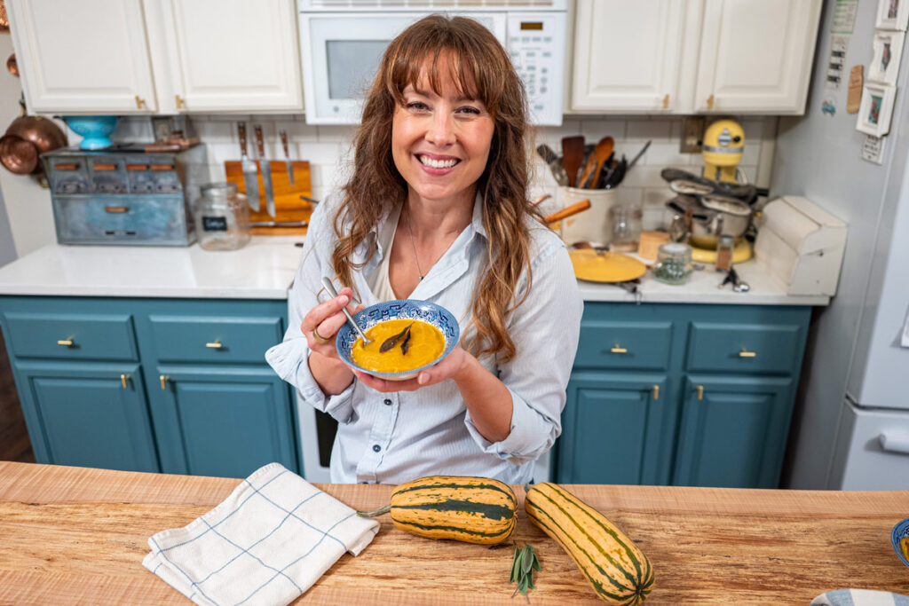 A woman holding a bowl of delicata squash soup.
