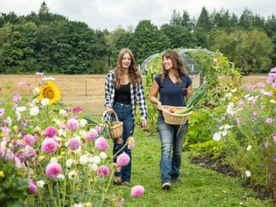A woman and her daughter walking through a garden.