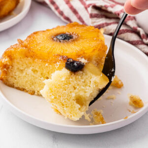 A slice of pineapple upside down cake with a bite on a fork to show texture.