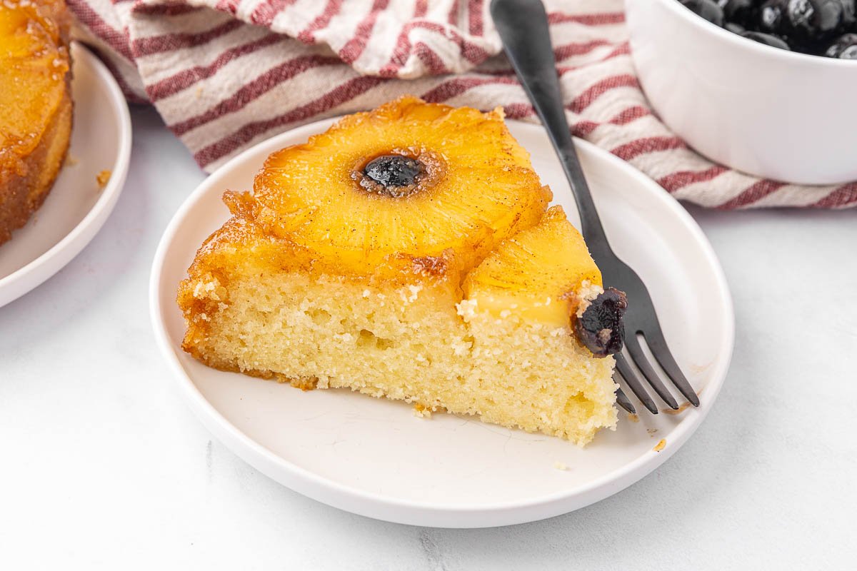 A slice of pineapple upside down cake served on a white plate.