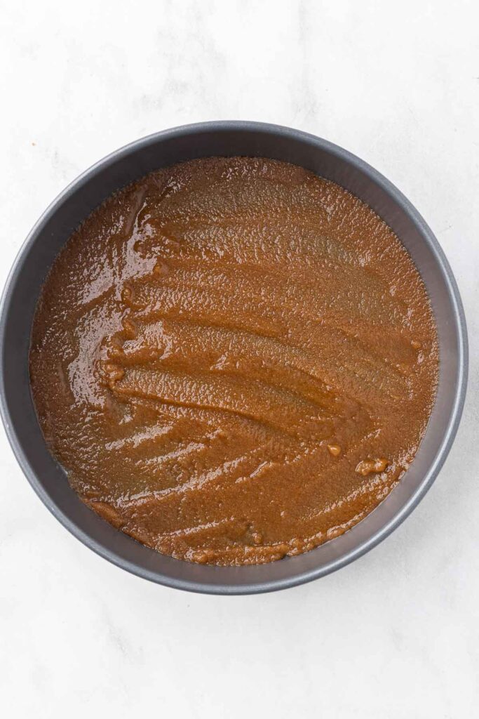 A layer of brown sugar topping spread on a round cake pan.