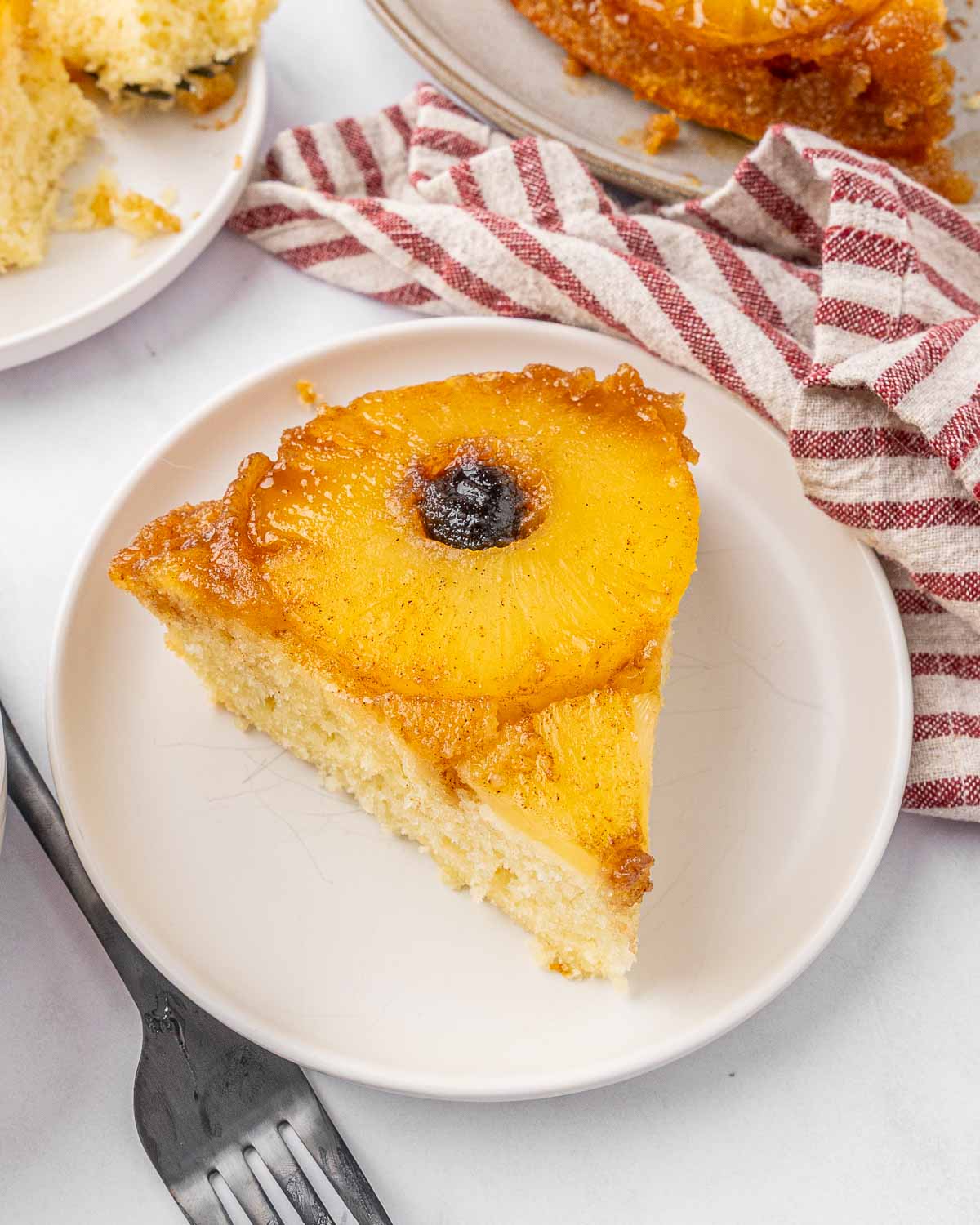 A slice of pineapple upside down cake served on a white plate.