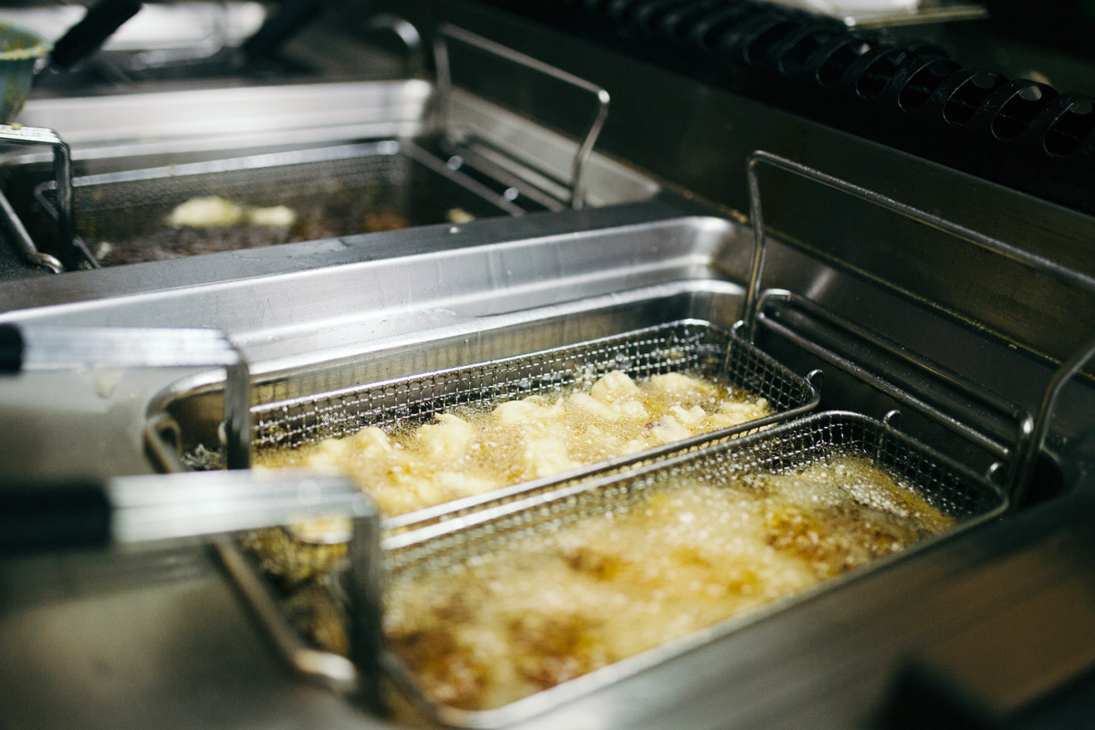 Restaurant fryer with food being cooked.