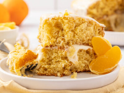 A slice of tangerine cake on a white plate garnished with segmented tangerines.