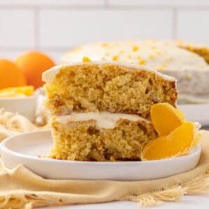 A slice of tangerine cake on a white plate garnished with segmented tangerines.