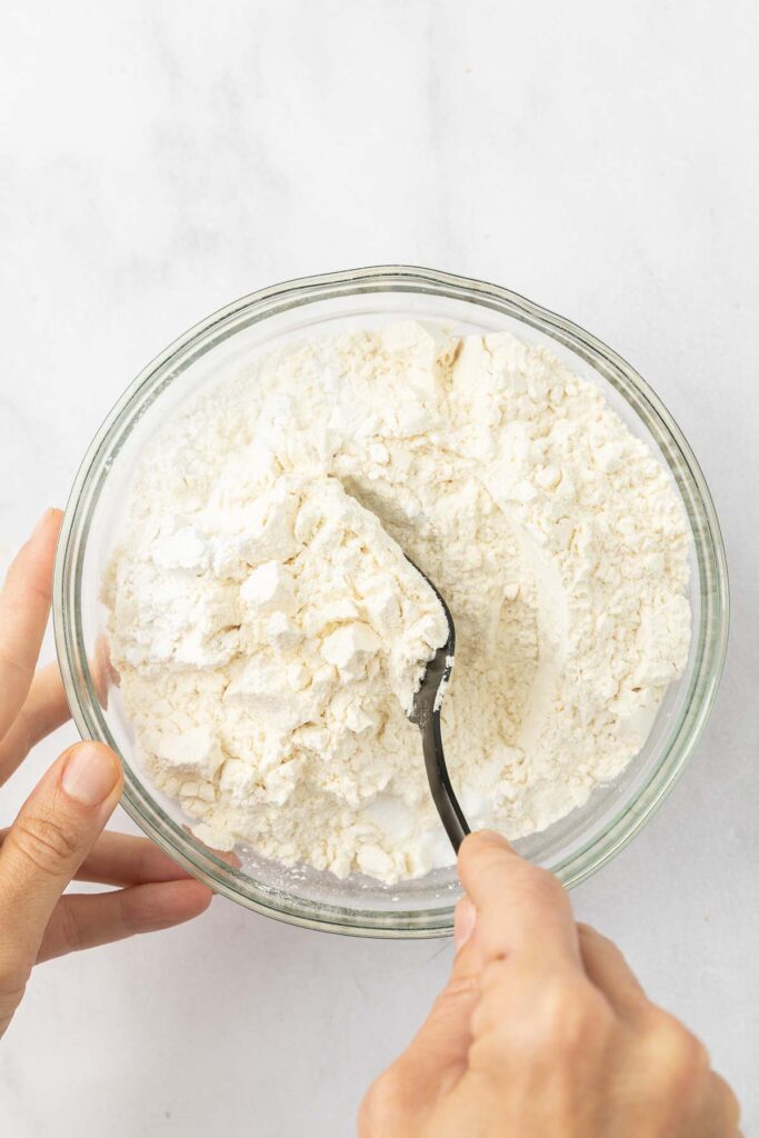 Tangerine cake dry ingredients in a bowl being mixed together with a fork.
