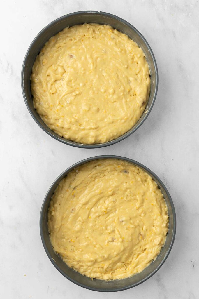 Tangerine cake batter divided equally among two nine inch cake pans.