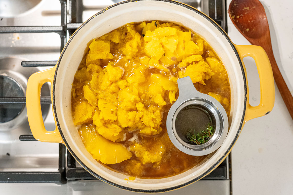 Herbs steeping in a Dutch oven with delicata squash soup.