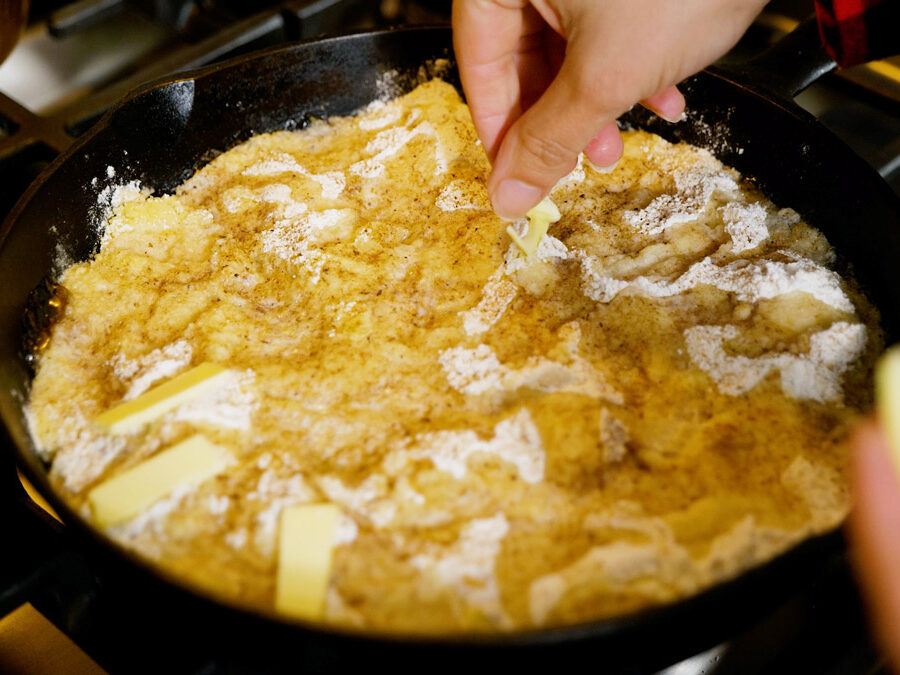 Dotting an apple pie dump cake with butter.