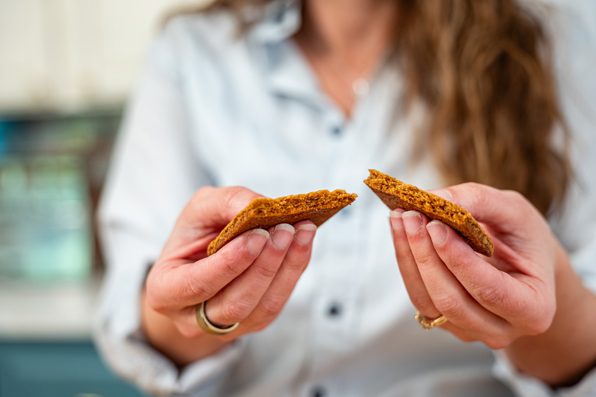 A woman snapping a graham cracker in half in her hands.