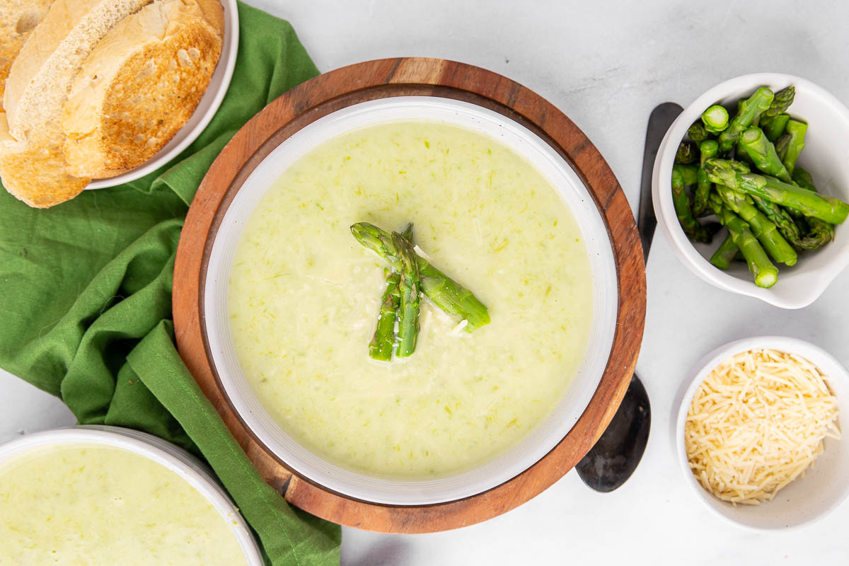 A bird's eye view of a bowl of creamy asparagus soup garnished with asparagus spears.