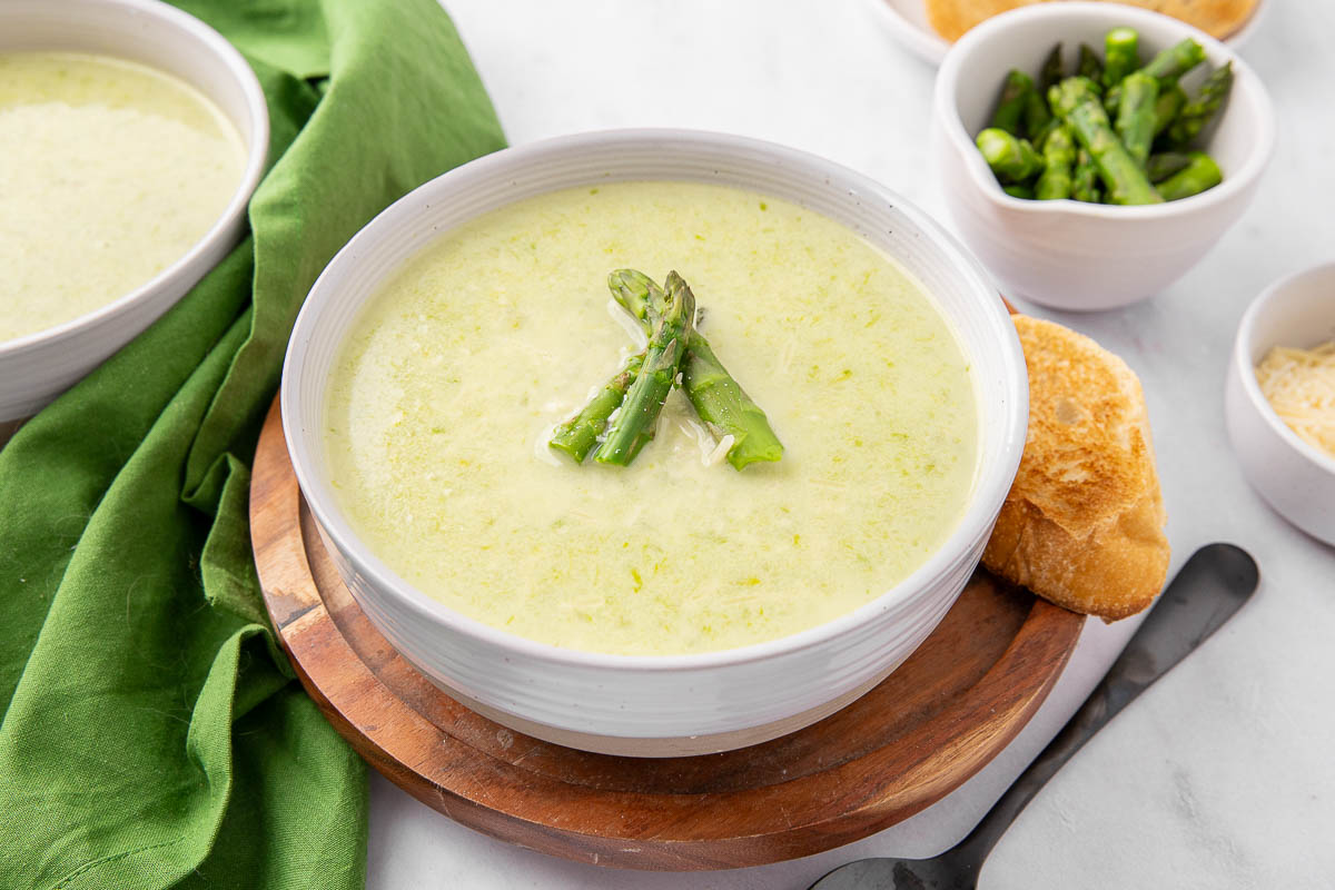 A bowl of creamy asparagus soup garnished with asparagus spears.