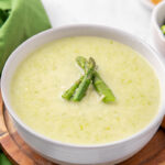 A bowl of creamy asparagus soup garnished with asparagus spears.