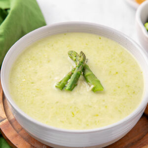 A bowl of creamy asparagus soup garnished with asparagus spears.