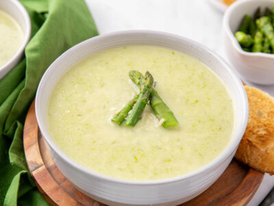 A bowl of creamy asparagus soup garnished with asparagus spears.