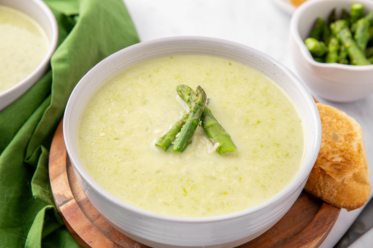 A bowl of creamy asparagus soup garnished with asparagus spears.