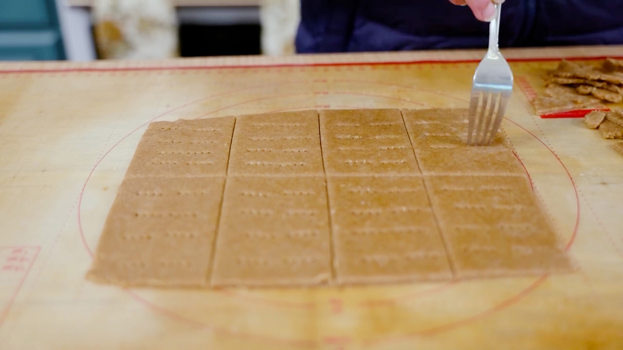 Pricking graham cracker dough with a fork.