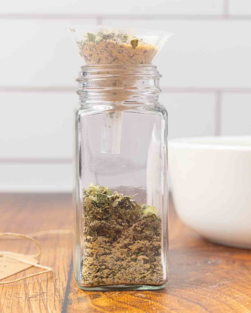 A jar topped with a funnel being filled with DIY ranch seasoning mix.