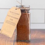A jar filled with DIY taco seasoning mix, and labeled with a tag.