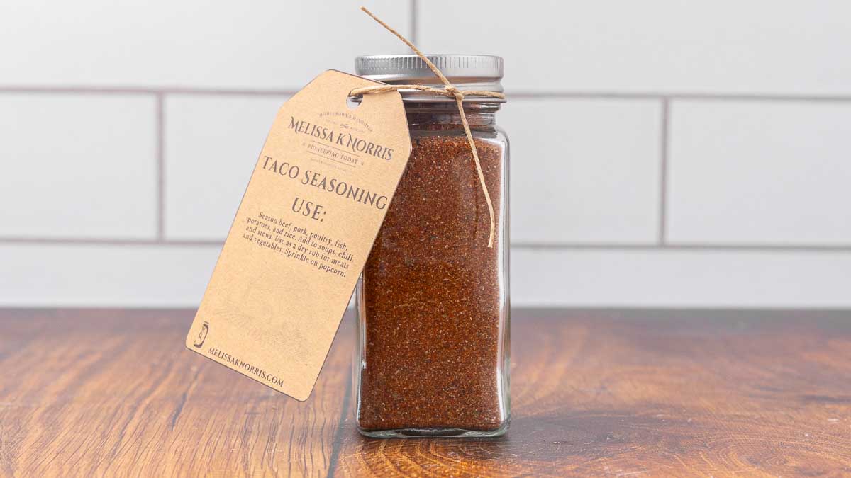 A jar filled with DIY taco seasoning mix, and labeled with a tag.