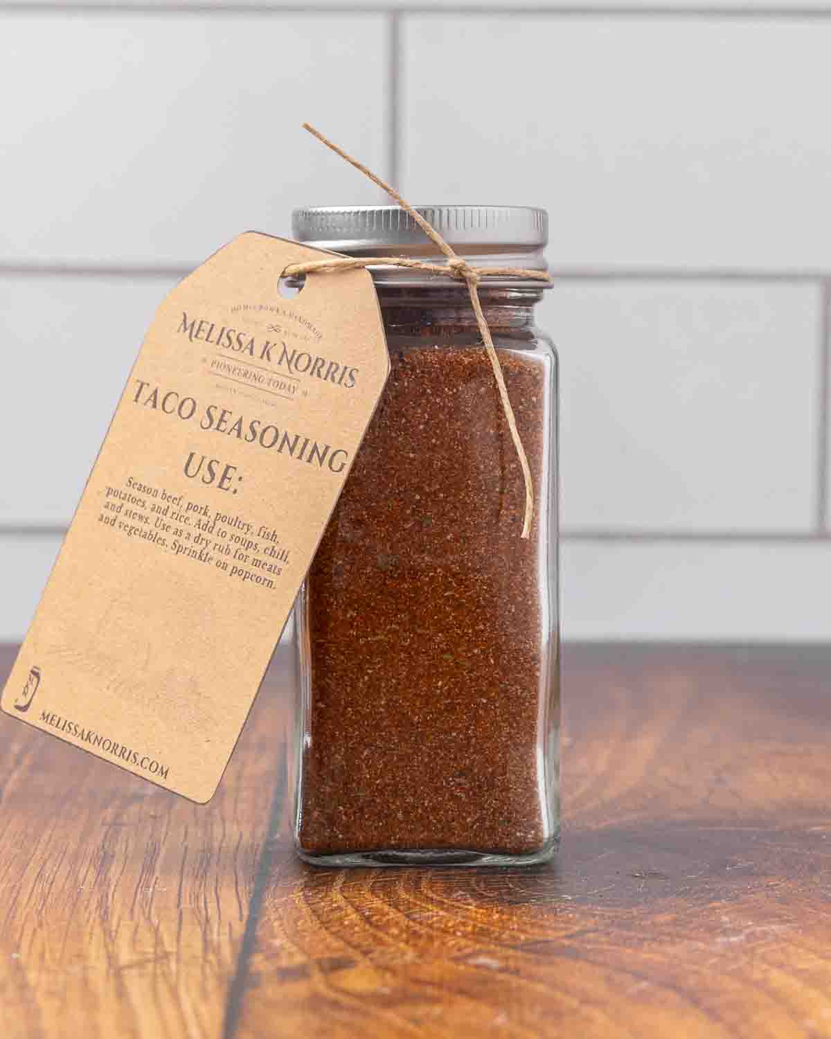 A jar filled with DIY taco seasoning mix, and labeled with a tag.