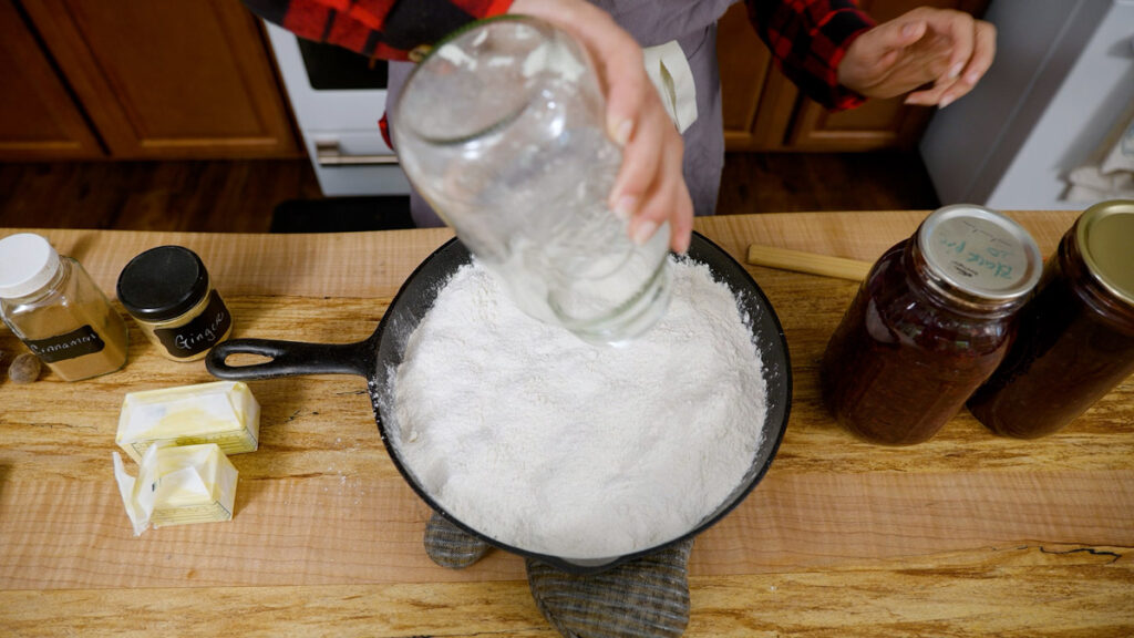 Dumping a jar of cake mix into a cast iron skillet.
