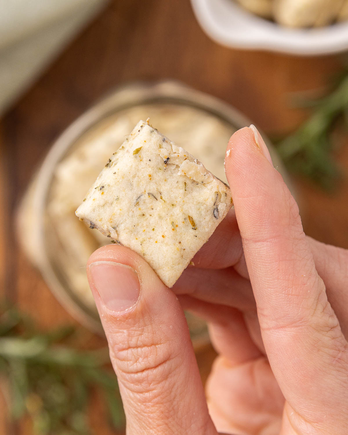 A hand pulling an Italian cracker from a glass jar.