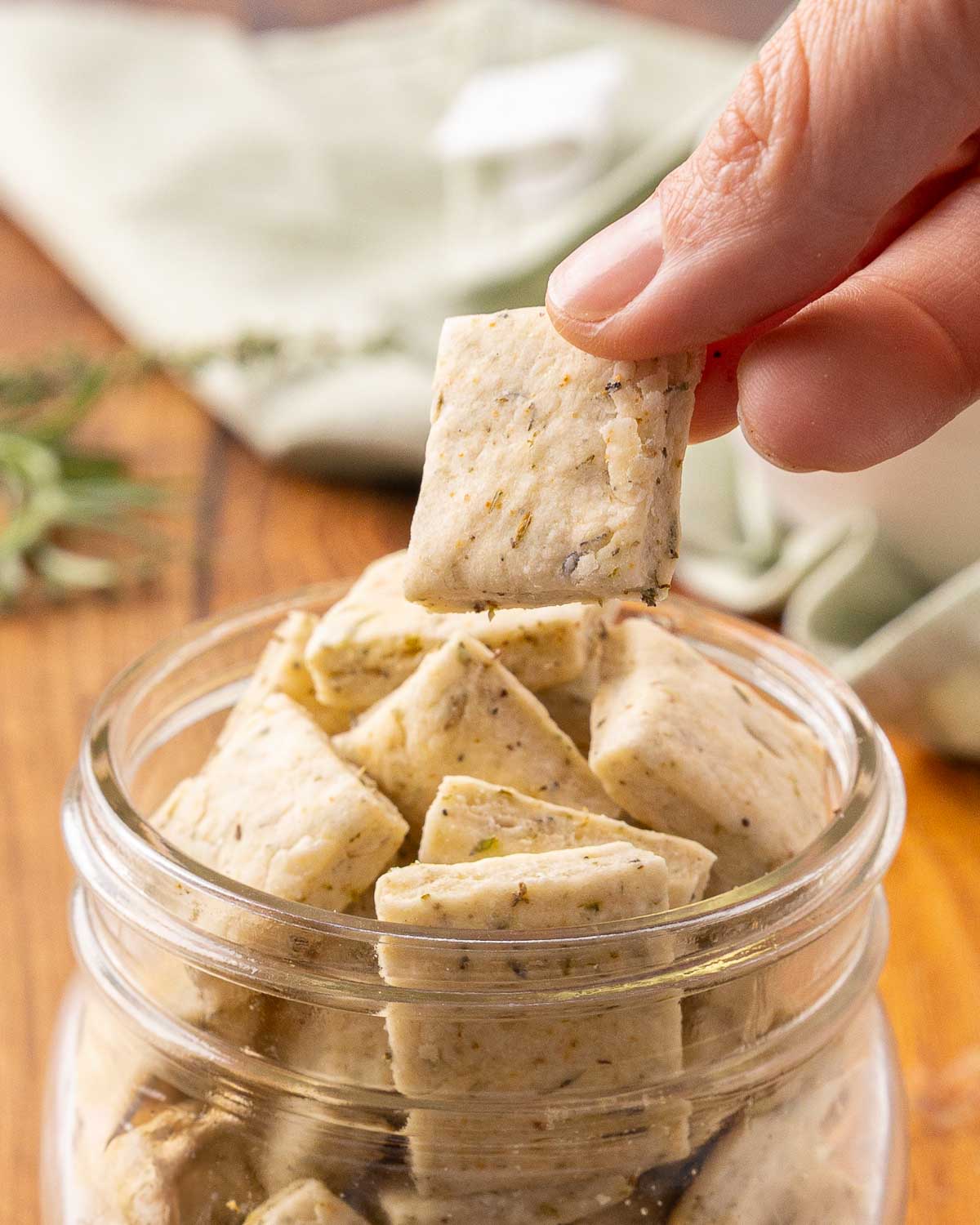 A hand pulling an Italian cracker from a glass jar.