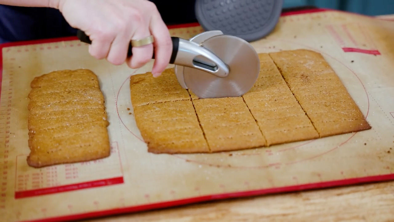 Scoring baked graham crackers into rectangles.