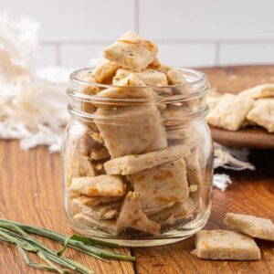 A glass jar full of sour cream and onion crackers.